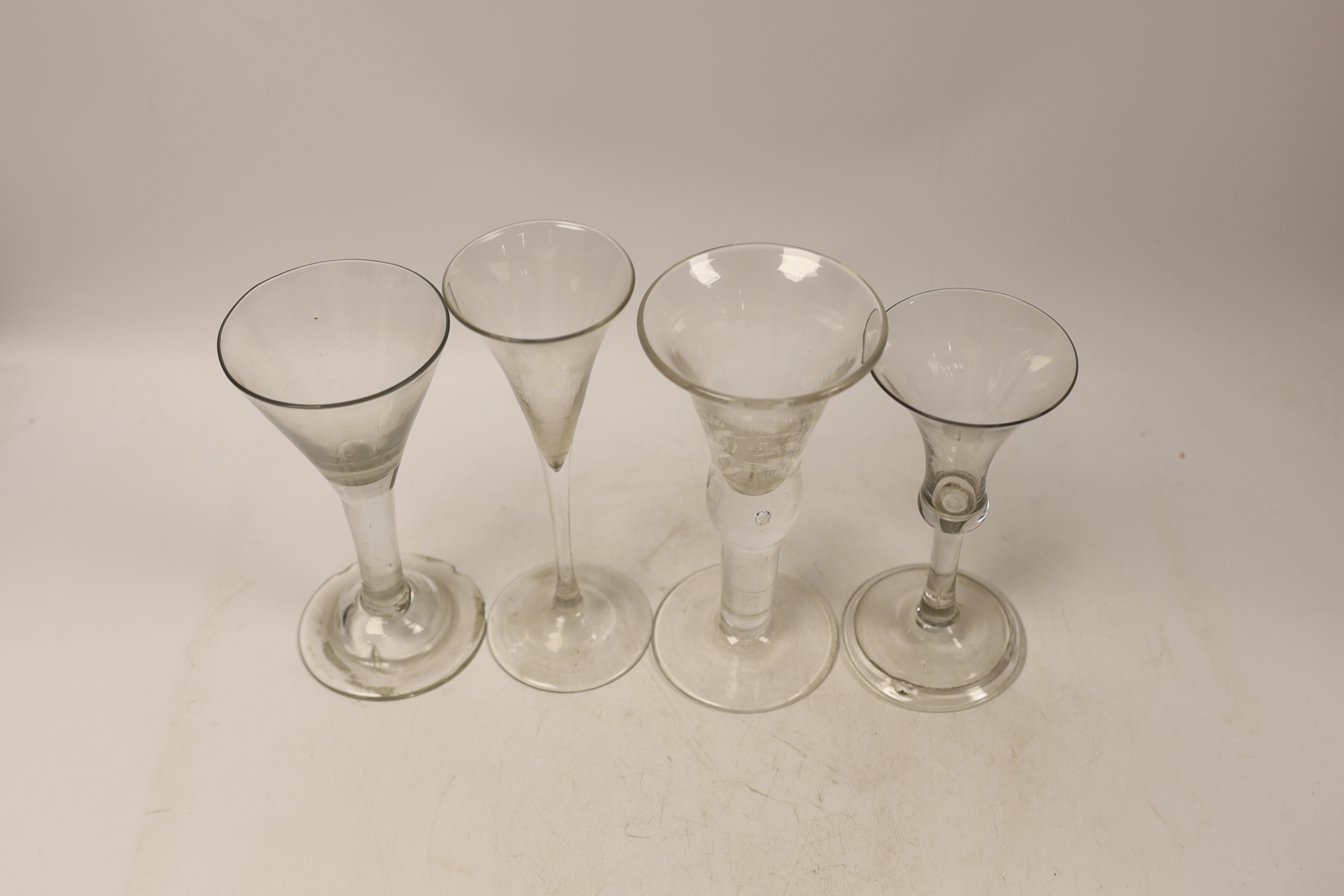 Three mid-18th century plain stem wine glasses, two with trumpet shaped bowls and a bell-shaped example with a folded foot, together with a reproduction drinking glass, tallest 20cm (4)